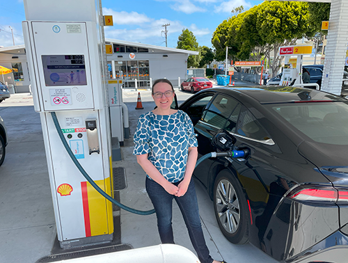 Dr. Groth stands next to a vehicle that is being filled at a hydrogen fueling station