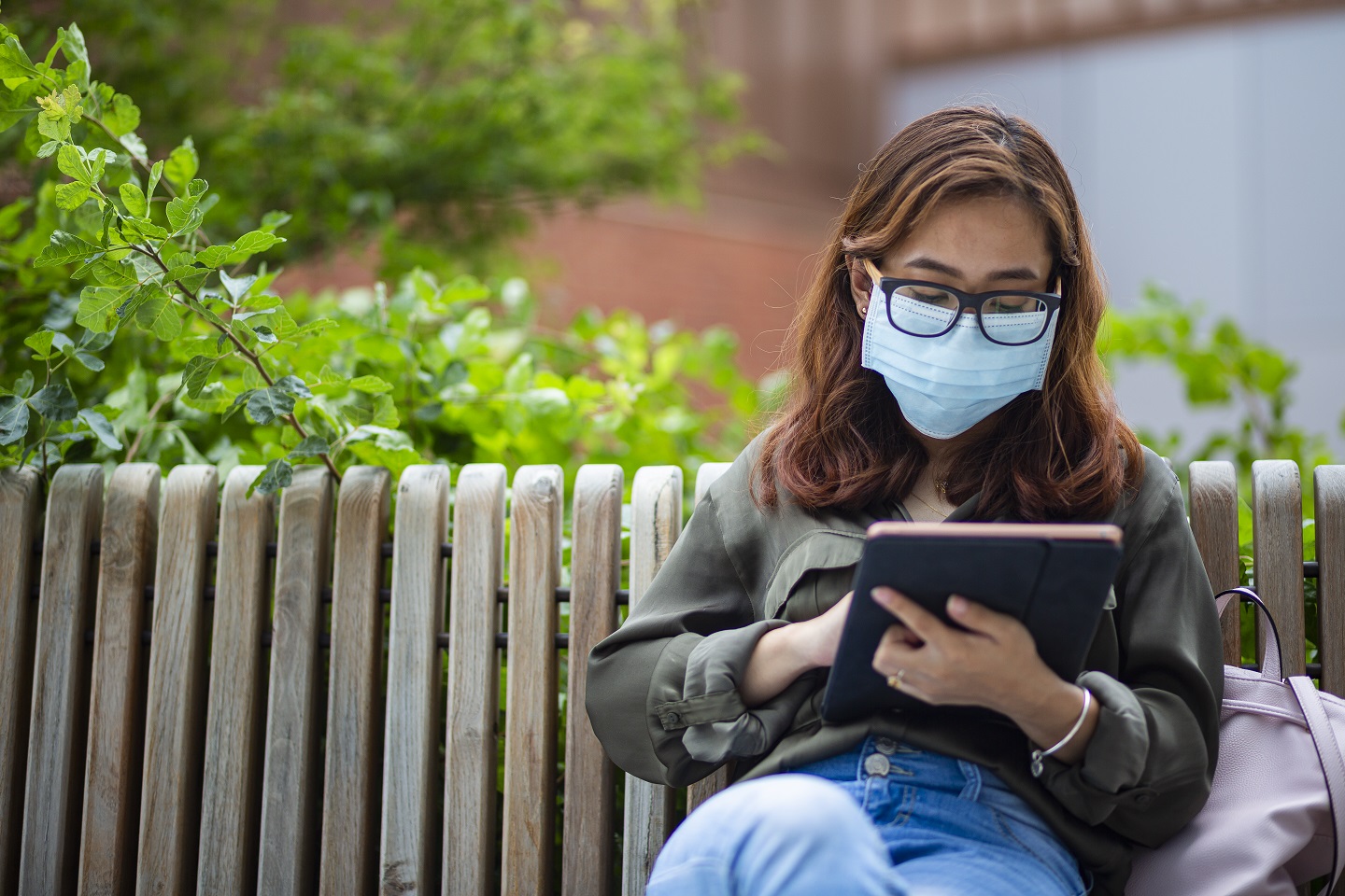 Student reading her tablet on the bench by the Brendan Iribe Center for Computer Science and Engineering