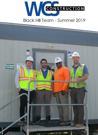 4 WCSC Black Hill team members summer standing outside construction trailer.