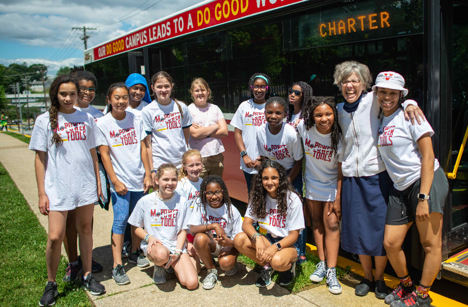 girls standing next to a bus