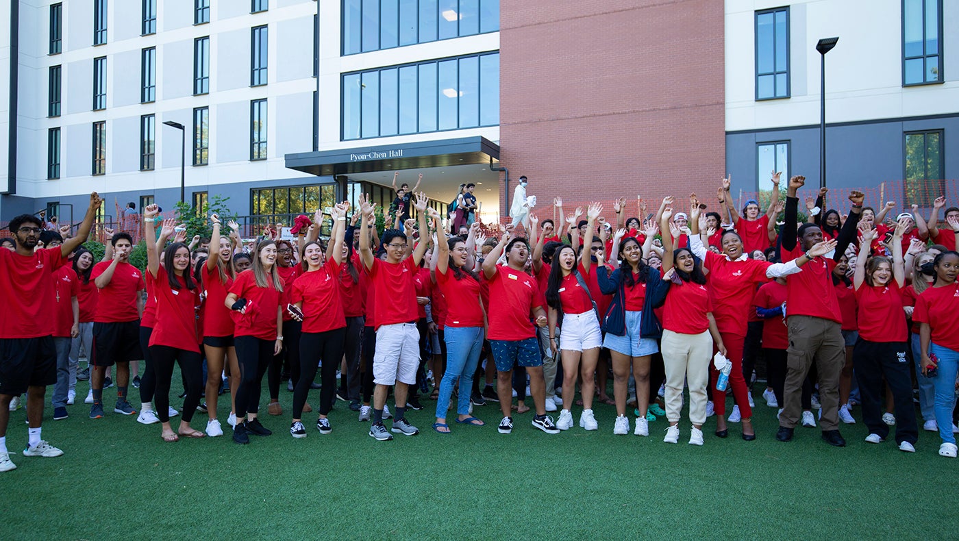 large group of students cheering in front of Pyon-Chen Hall during dedication ceremony